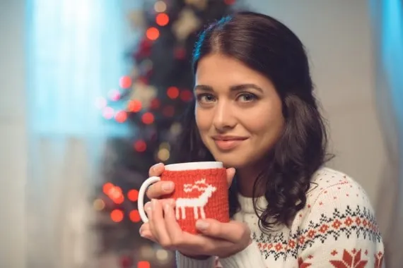 Ung kvinde i julesweater med en kop varm kakao